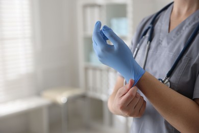 Photo of Medical worker putting gloves in hospital, closeup. Space for text