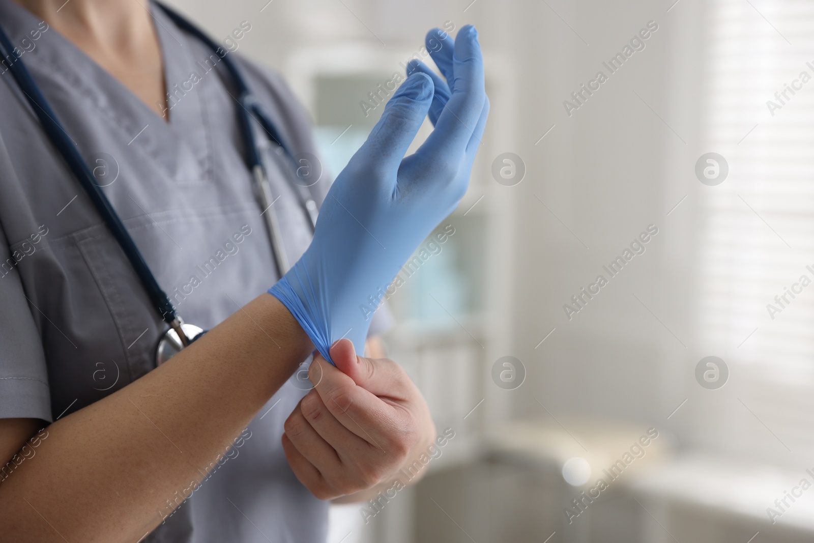 Photo of Medical worker putting gloves in hospital, closeup. Space for text