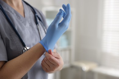 Photo of Medical worker putting gloves in hospital, closeup. Space for text