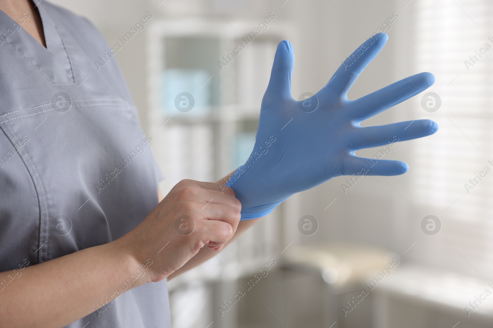 Photo of Medical worker putting gloves in hospital, closeup