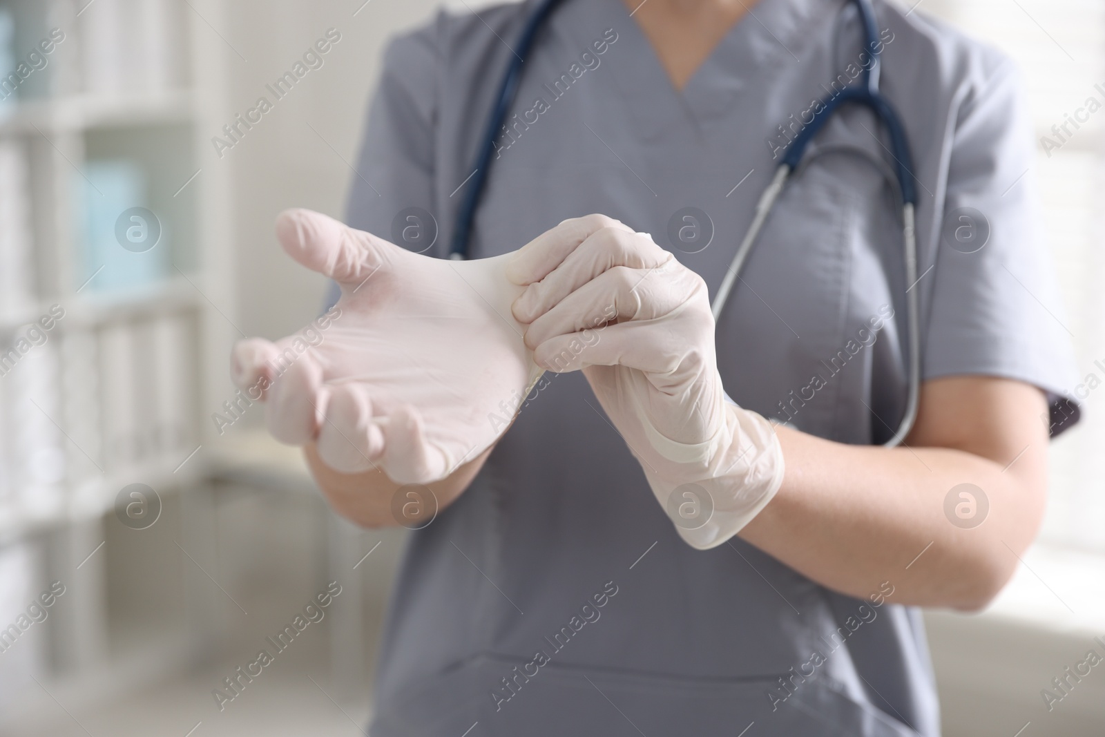 Photo of Medical worker putting gloves in hospital, closeup