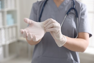 Photo of Medical worker putting gloves in hospital, closeup