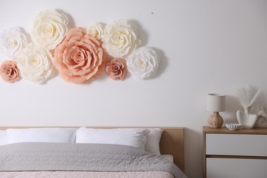 Beautiful decorative paper flowers on wall in bedroom