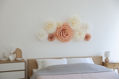 Beautiful decorative paper flowers on wall in bedroom