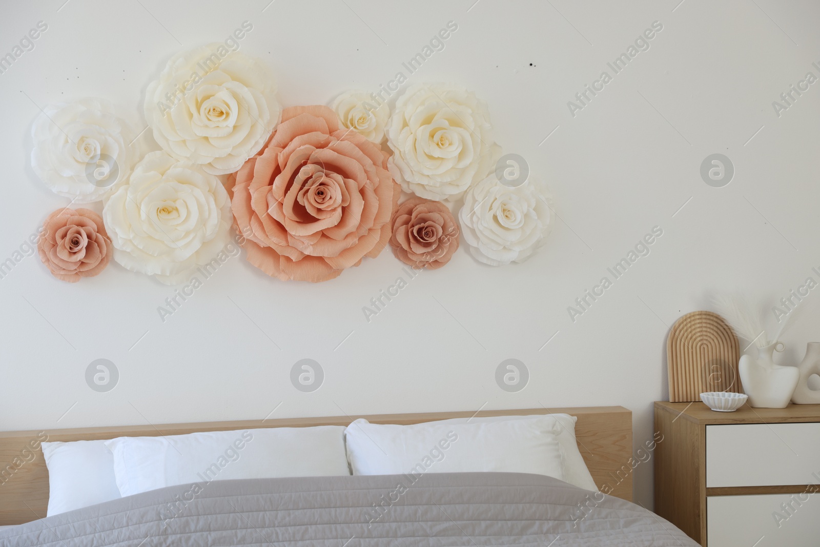 Photo of Beautiful decorative paper flowers on wall in bedroom