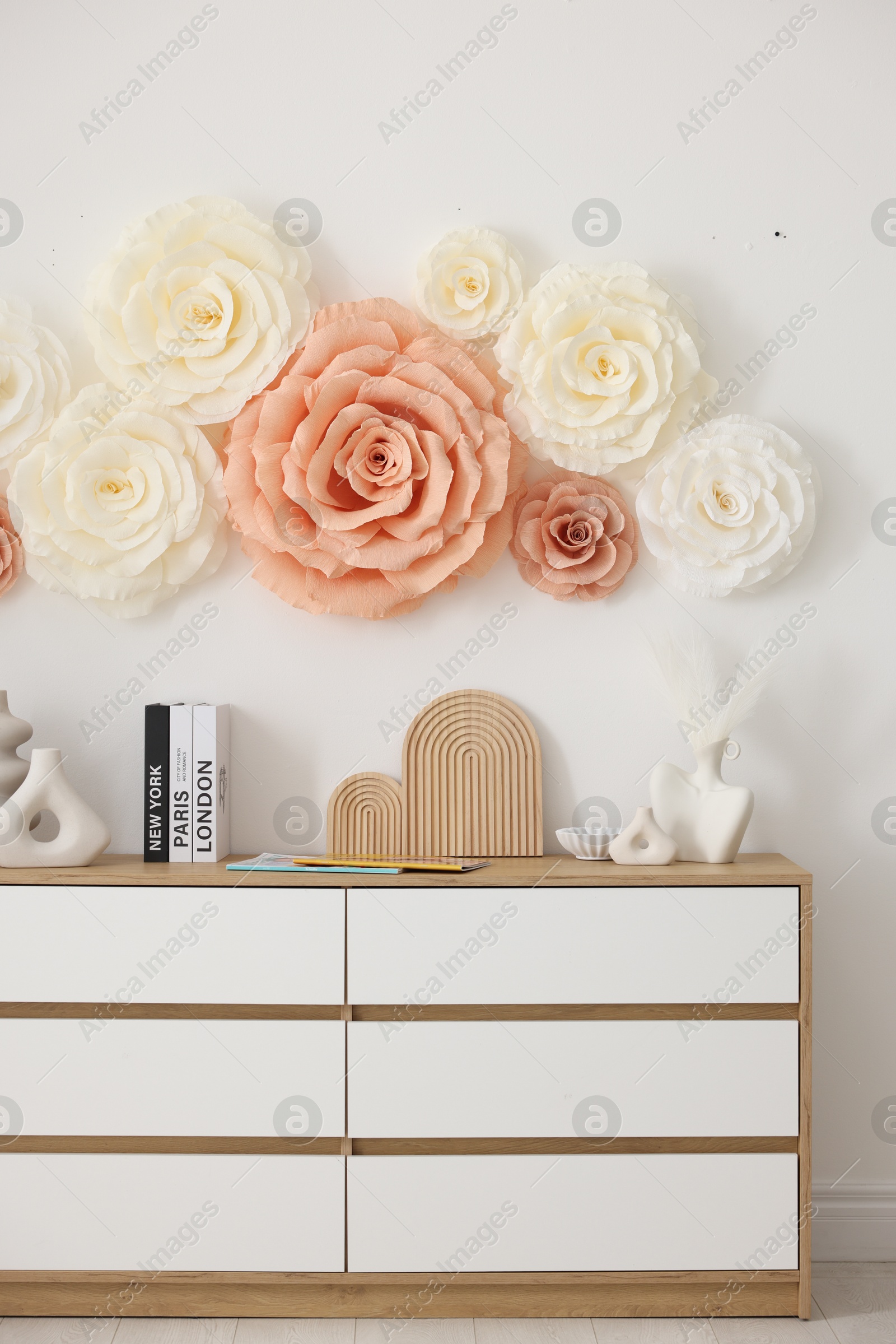 Photo of Beautiful decorative paper flowers on wall in room