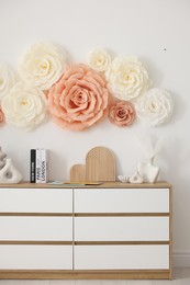 Photo of Beautiful decorative paper flowers on wall in room