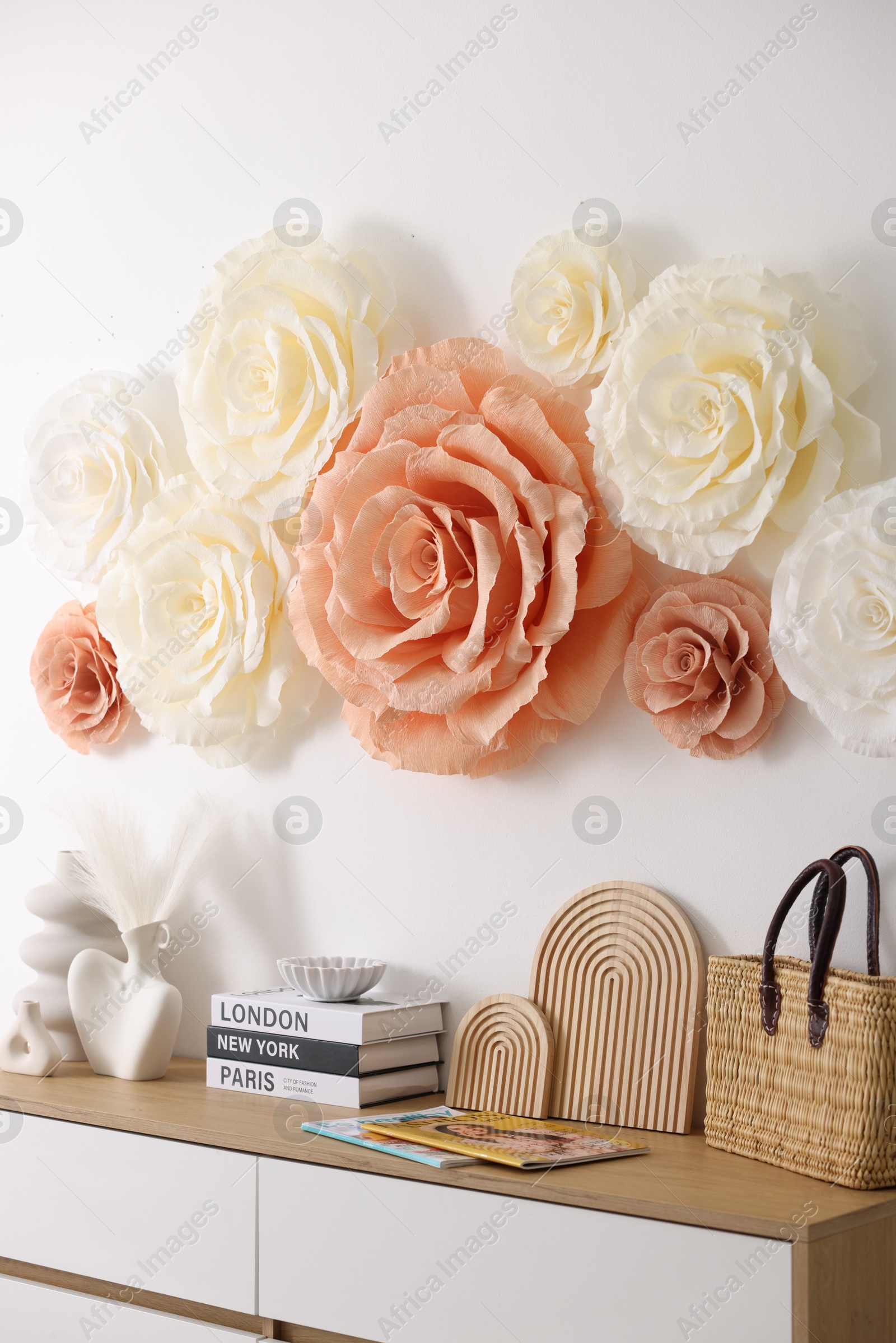 Photo of Beautiful decorative paper flowers on wall in room