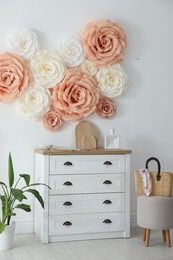 Photo of Beautiful decorative paper flowers on wall in room