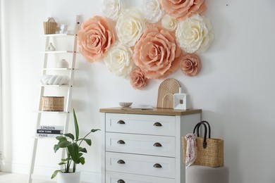 Photo of Beautiful decorative paper flowers on wall in room