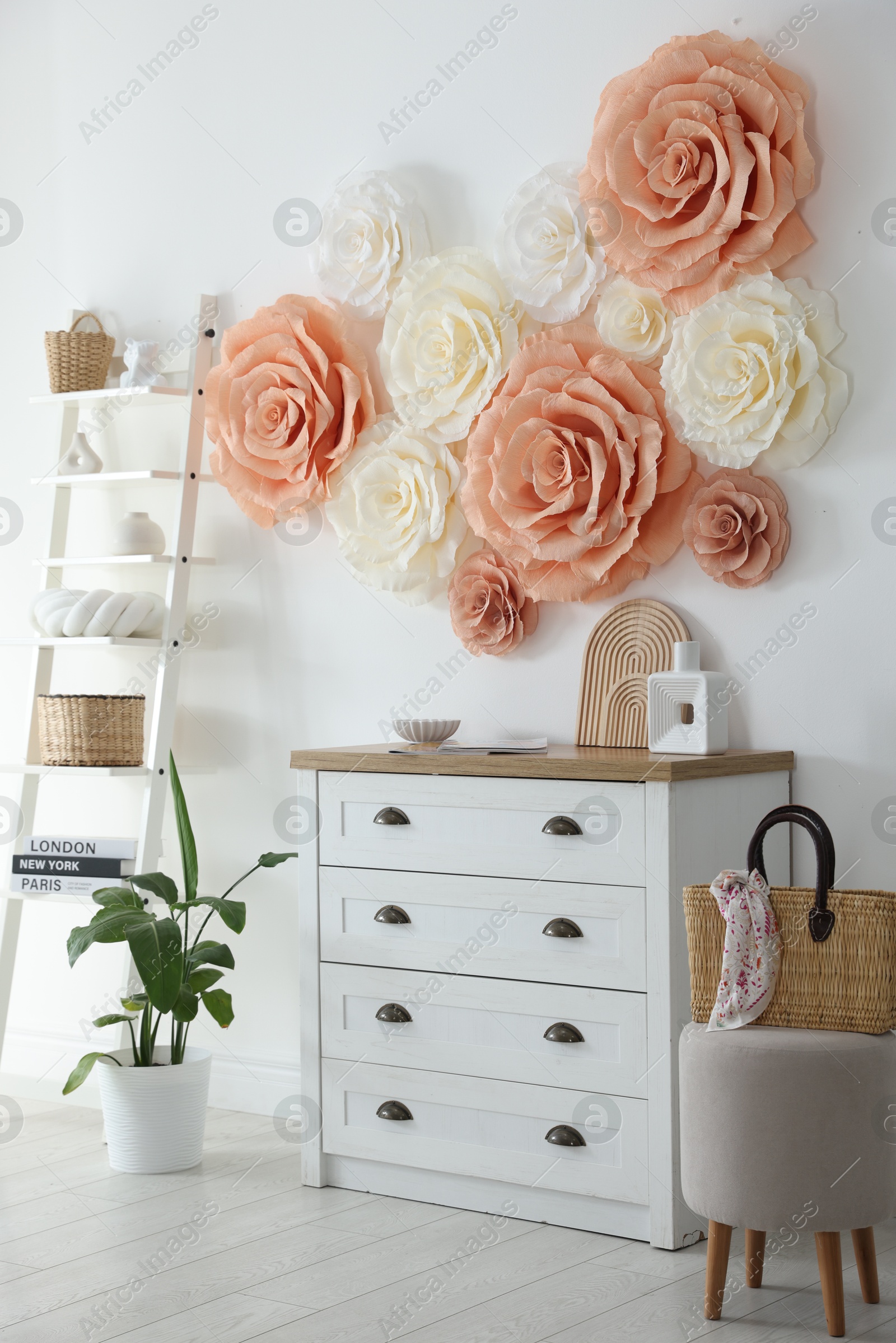 Photo of Beautiful decorative paper flowers on wall in room