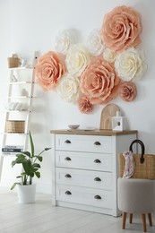 Beautiful decorative paper flowers on wall in room