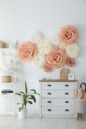 Photo of Beautiful decorative paper flowers on wall in room