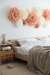 Beautiful decorative paper flowers on wall in bedroom