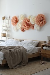 Beautiful decorative paper flowers on wall in bedroom