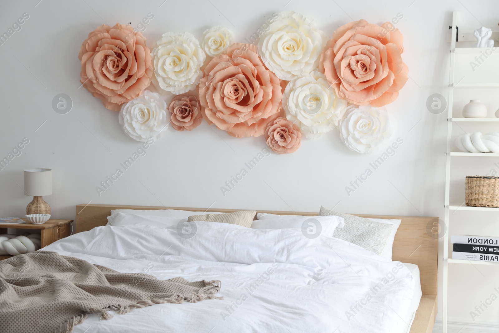 Photo of Beautiful decorative paper flowers on wall in bedroom