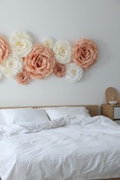 Photo of Beautiful decorative paper flowers on wall in bedroom