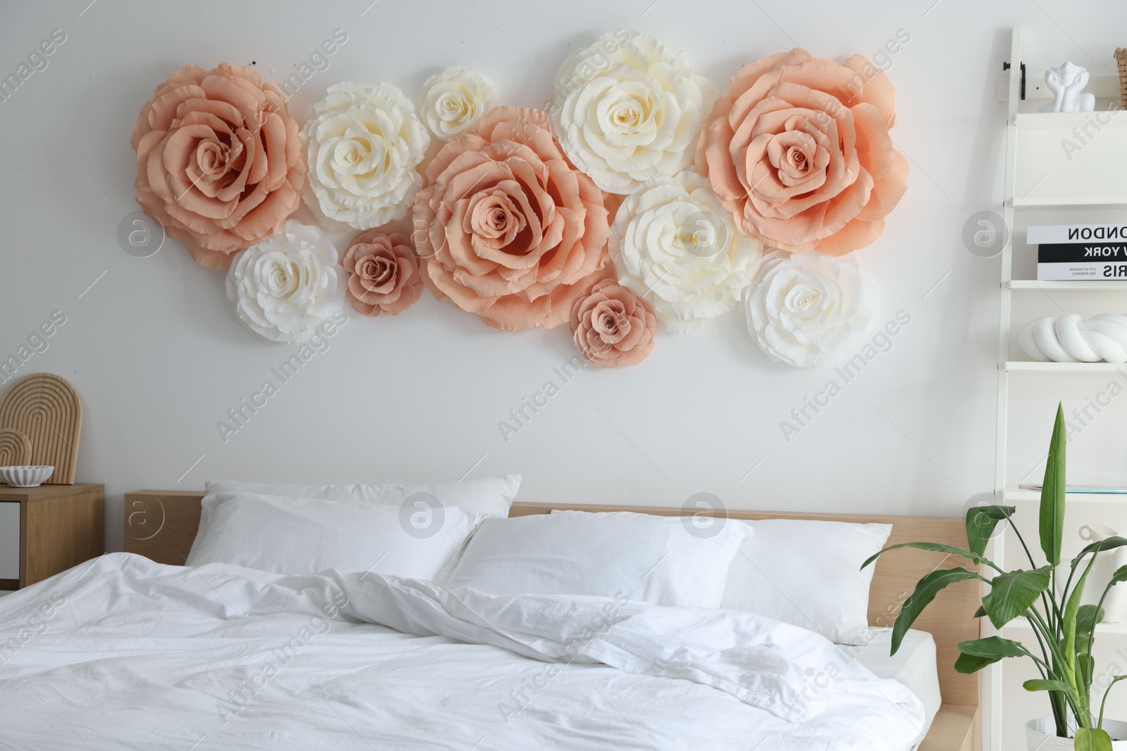 Photo of Beautiful decorative paper flowers on wall in bedroom