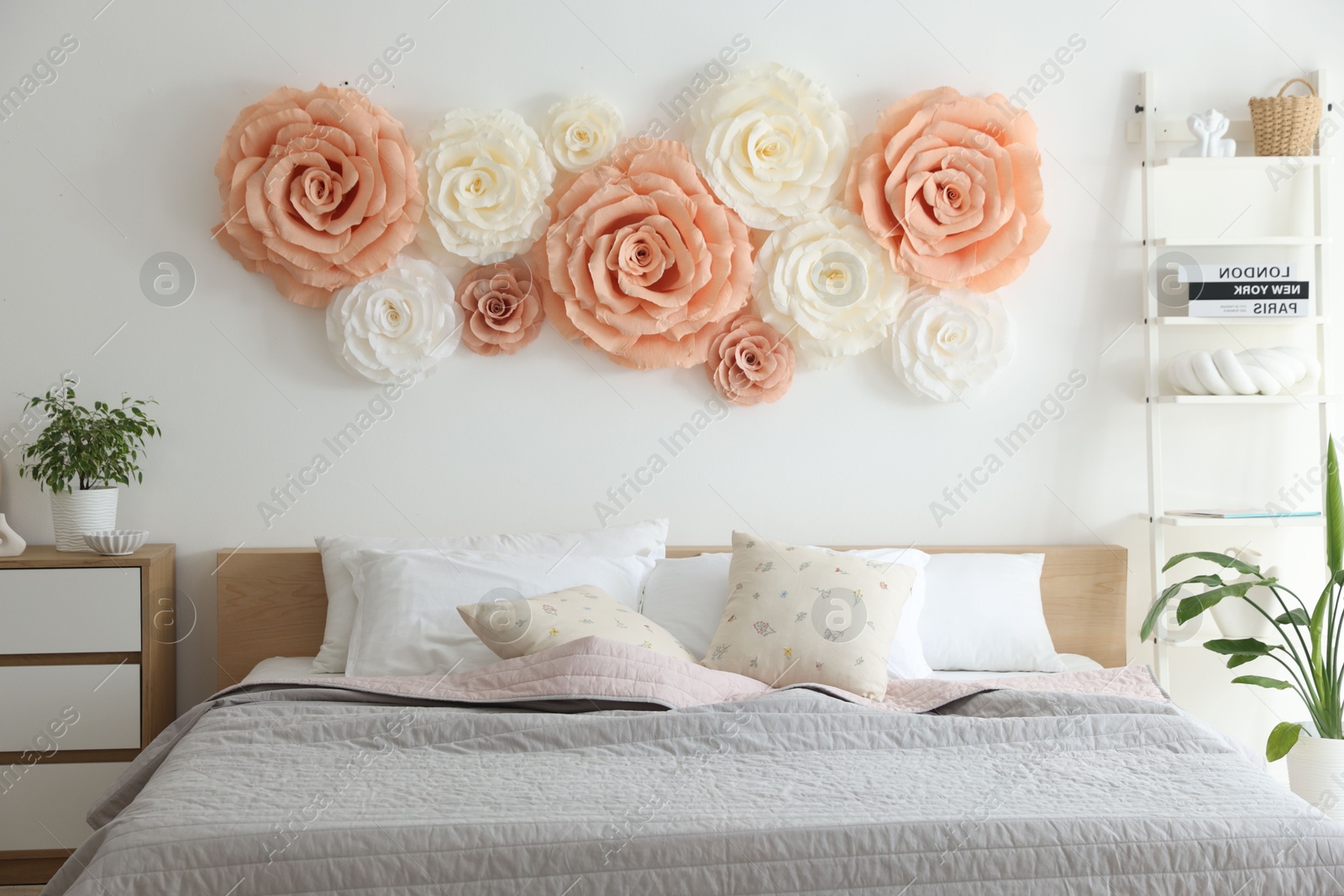 Photo of Beautiful decorative paper flowers on wall in bedroom