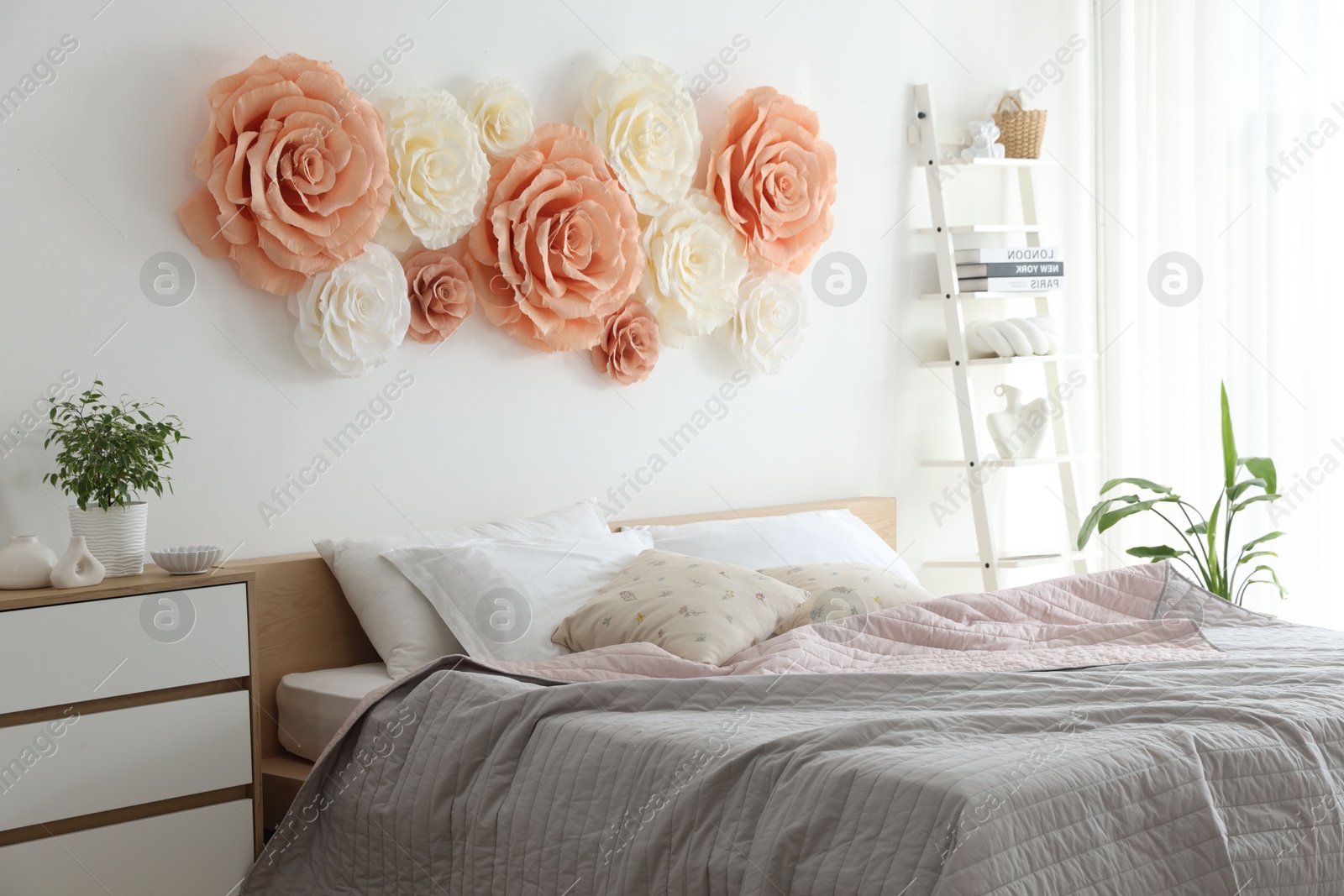 Photo of Beautiful decorative paper flowers on wall in bedroom