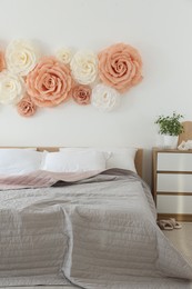 Photo of Beautiful decorative paper flowers on wall in bedroom