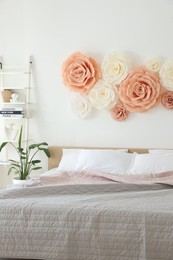 Photo of Beautiful decorative paper flowers on wall in bedroom