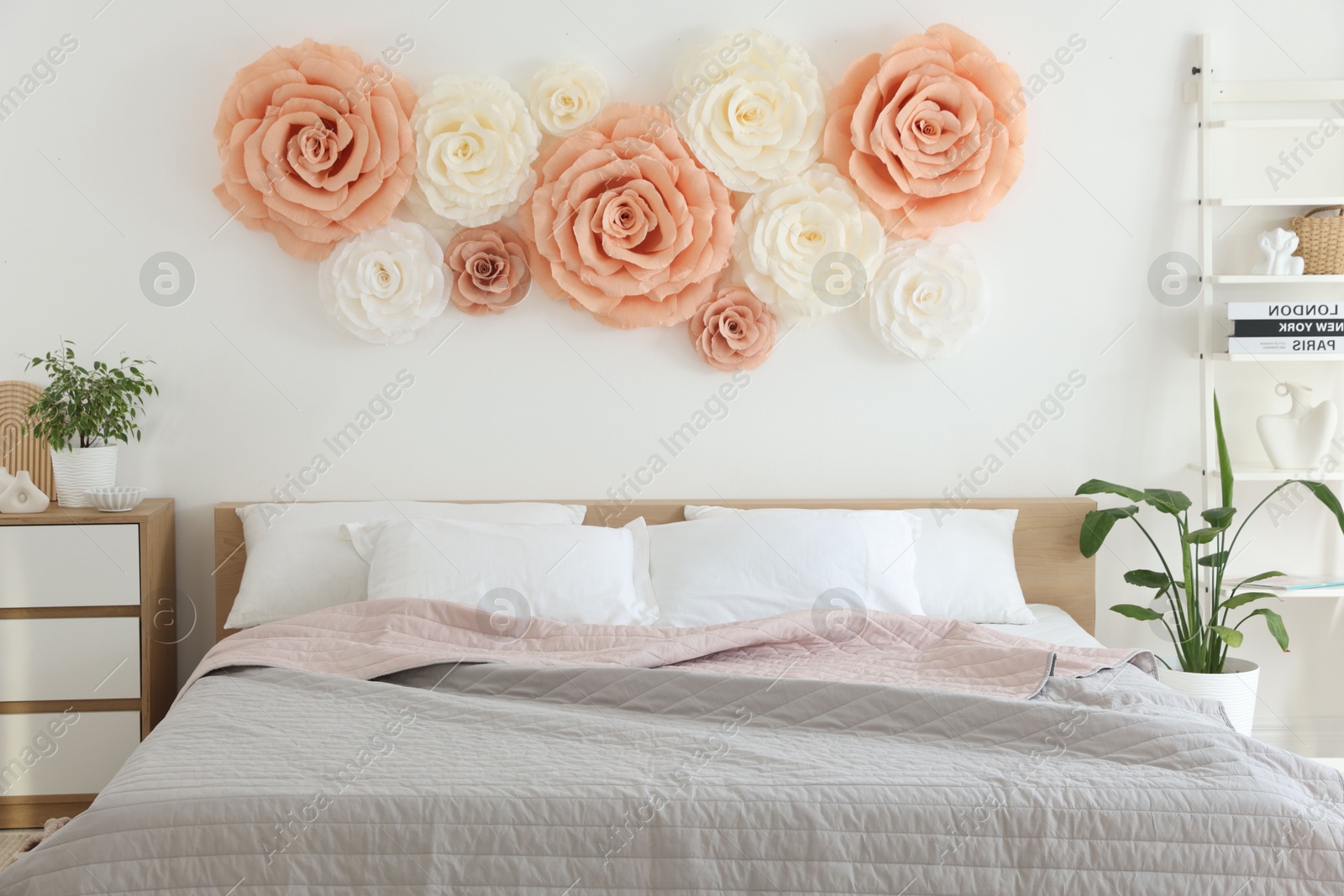 Photo of Beautiful decorative paper flowers on wall in bedroom