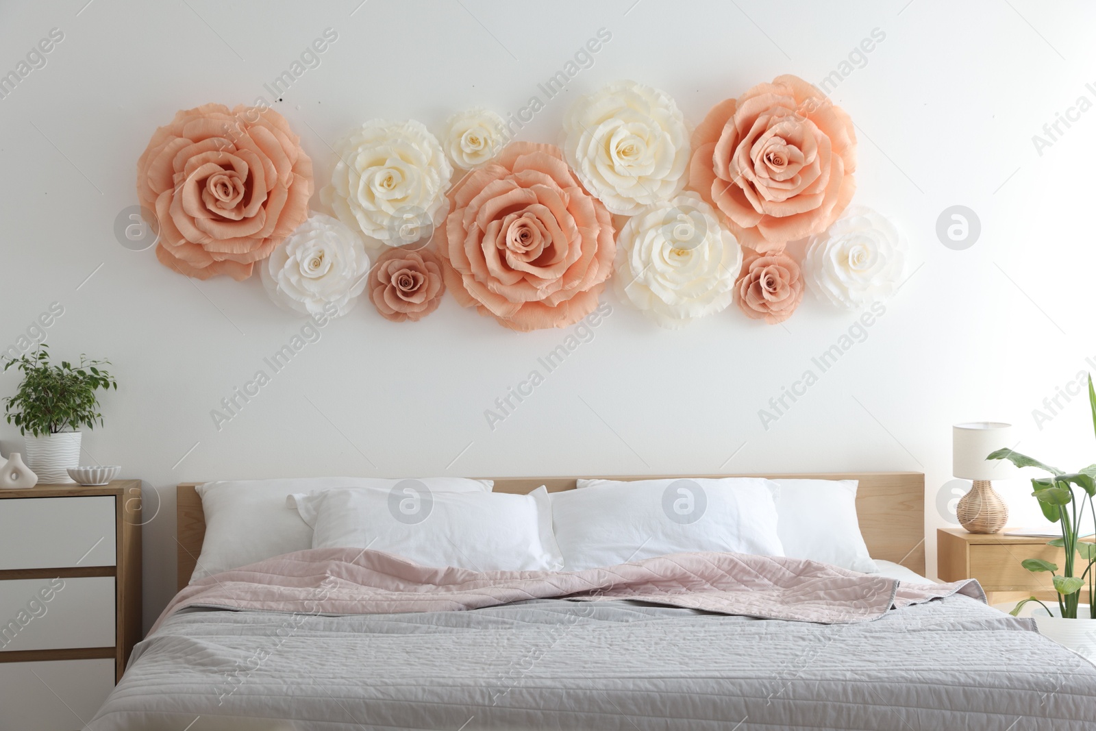 Photo of Beautiful decorative paper flowers on wall in bedroom