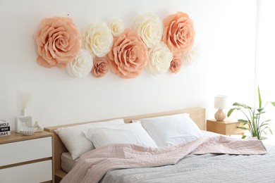 Photo of Beautiful decorative paper flowers on wall in bedroom