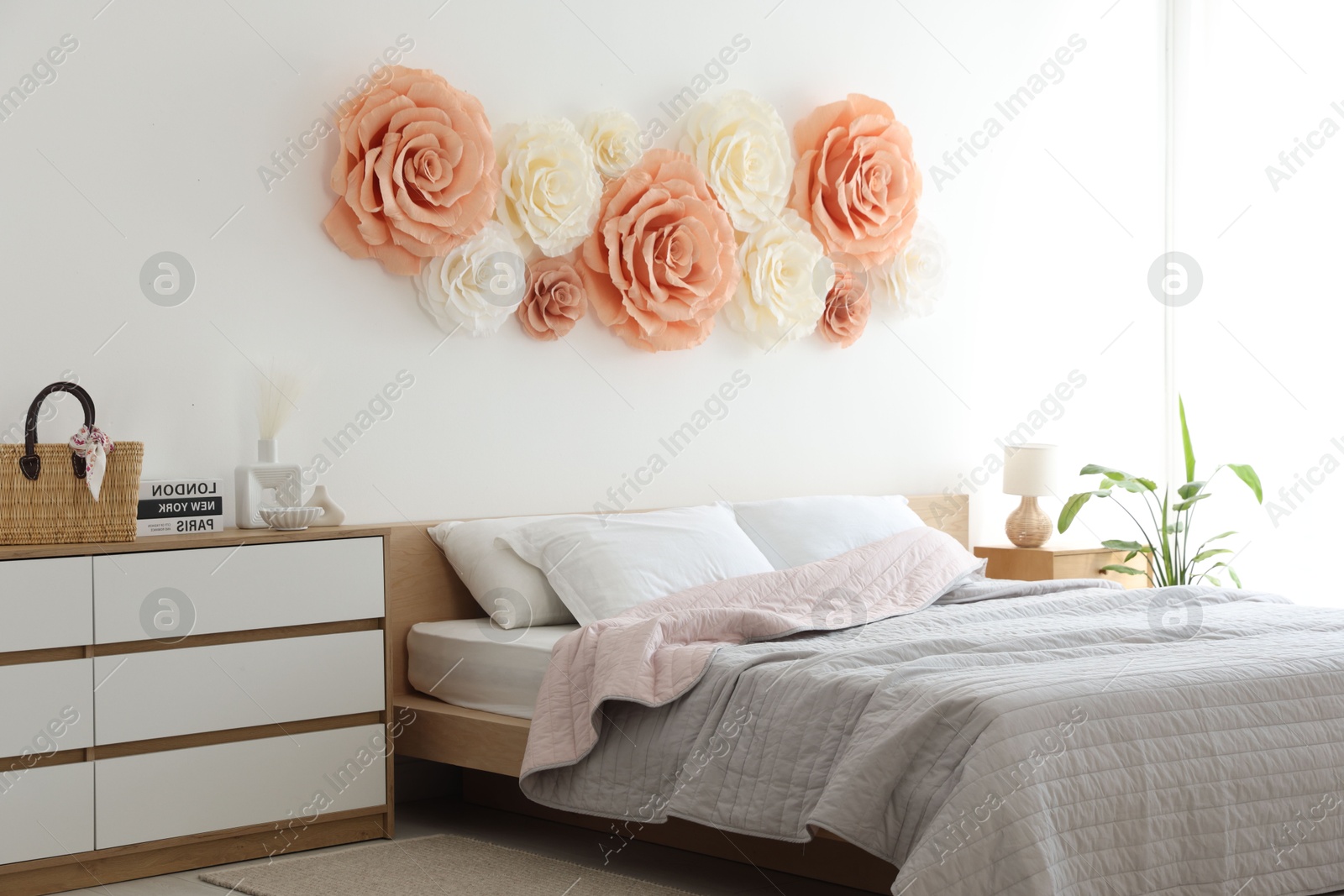 Photo of Beautiful decorative paper flowers on wall in bedroom