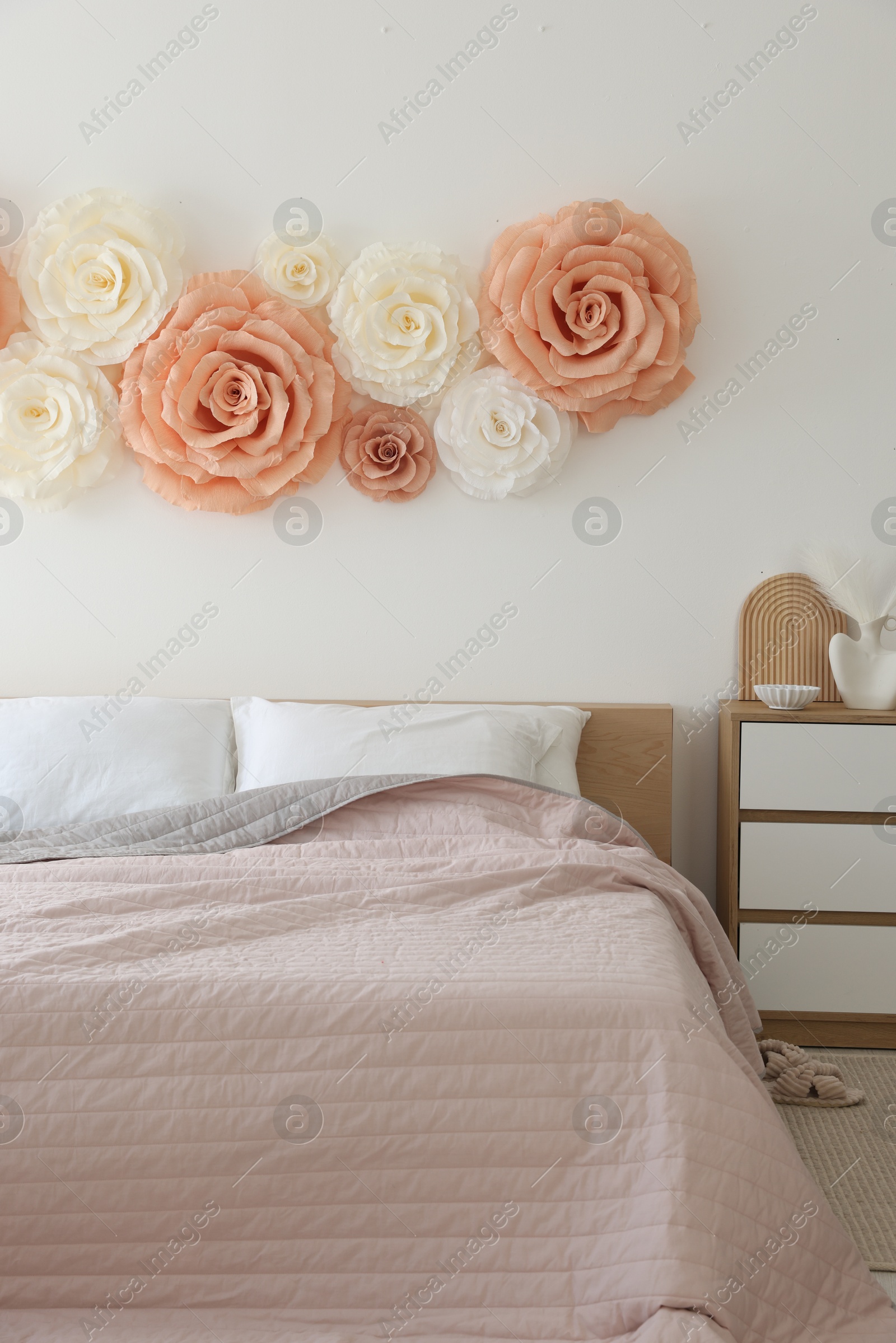 Photo of Beautiful decorative paper flowers on wall in bedroom