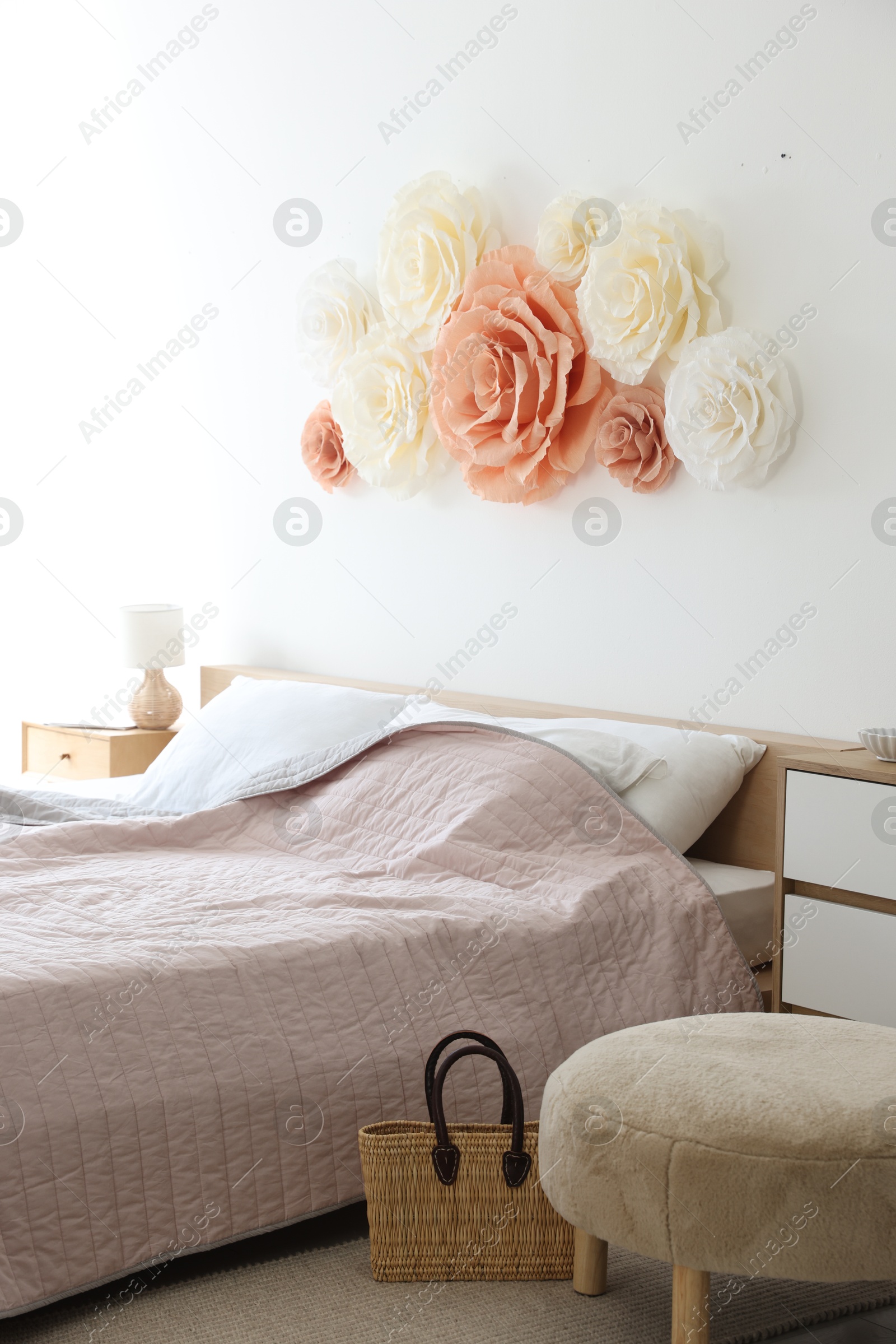 Photo of Beautiful decorative paper flowers on wall in bedroom