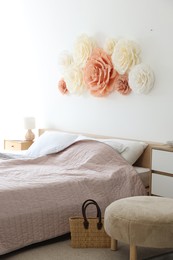 Photo of Beautiful decorative paper flowers on wall in bedroom