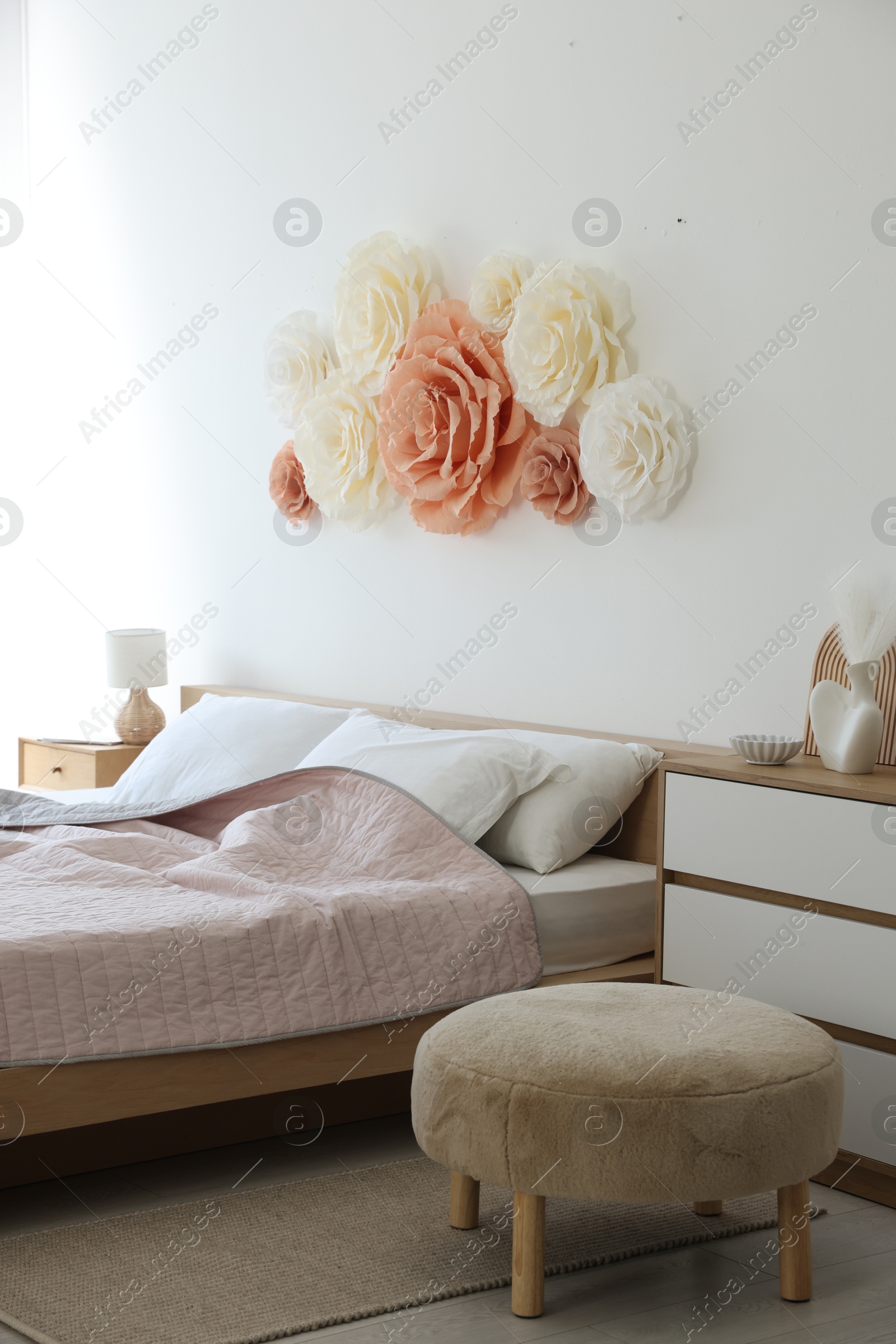 Photo of Beautiful decorative paper flowers on wall in bedroom