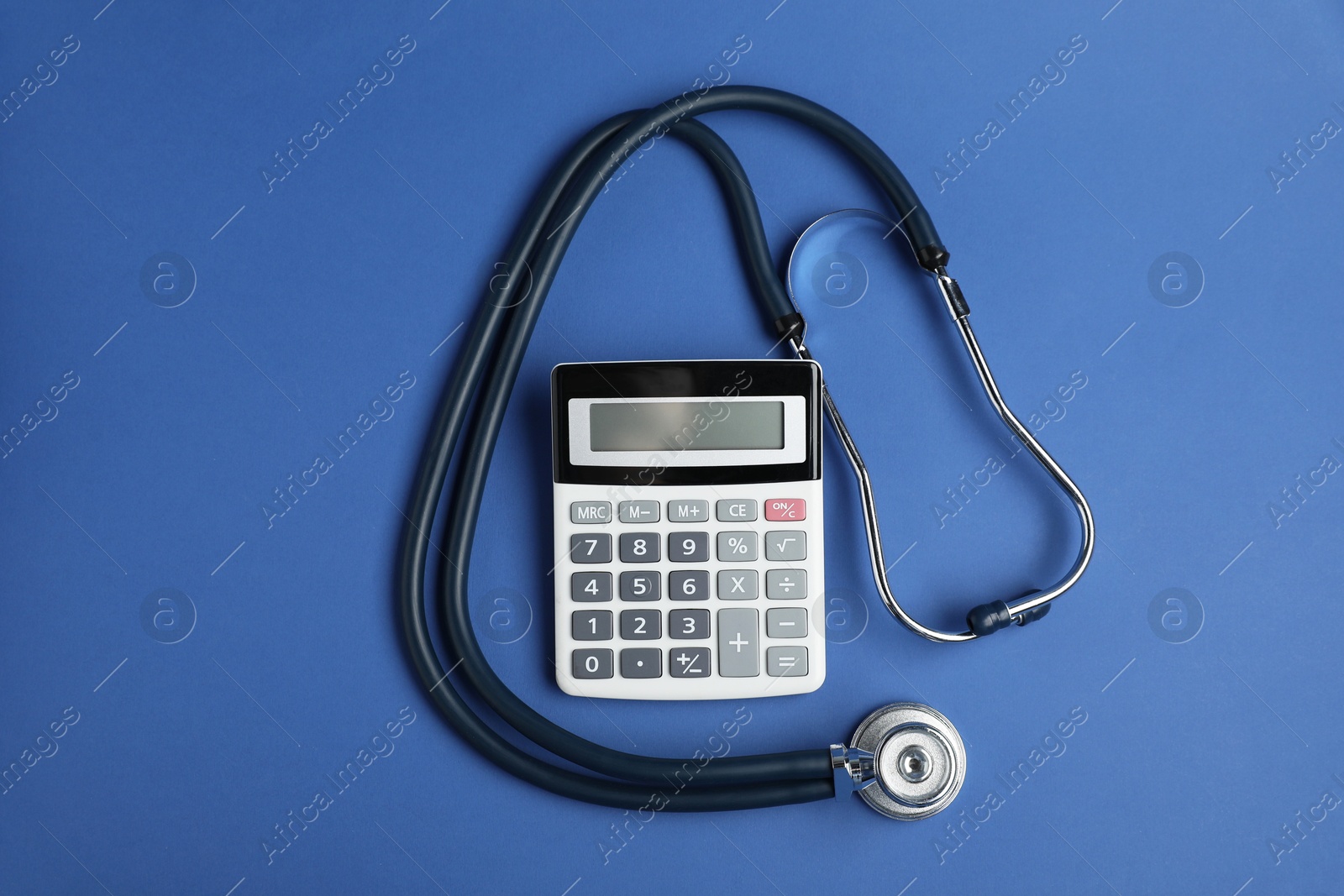 Stethoscope and calculator on blue background, top view Photo of Stethoscope and calculator on blue background, top view
