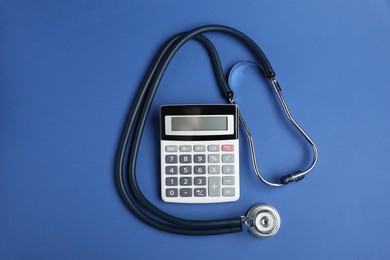 Photo of Stethoscope and calculator on blue background, top view