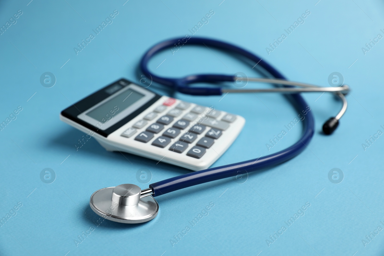 Stethoscope and calculator on light blue background, closeup Photo of Stethoscope and calculator on light blue background, closeup