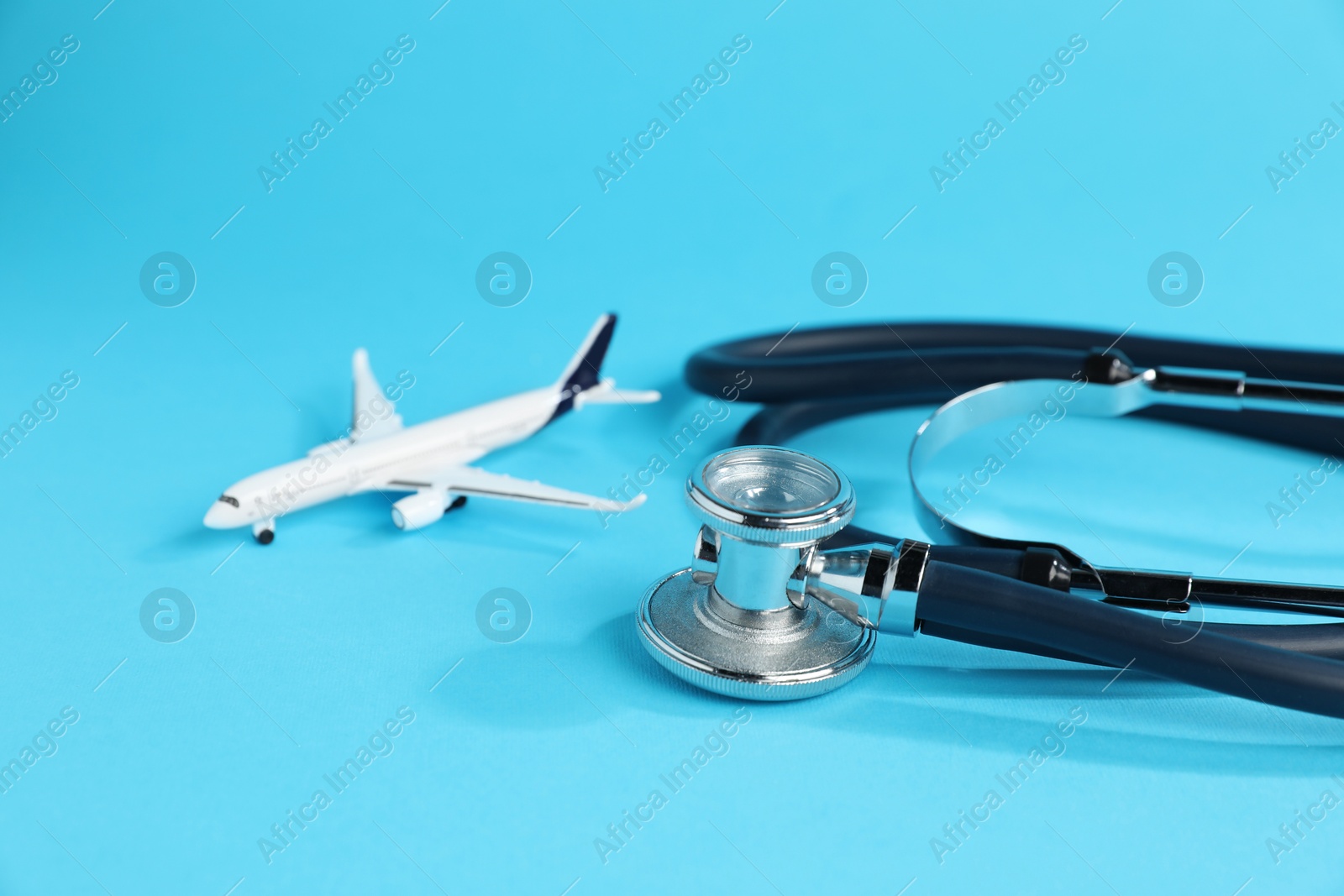 Stethoscope and airplane model on light blue background, closeup Photo of Stethoscope and airplane model on light blue background, closeup