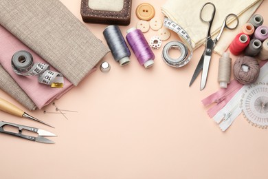 Different sewing supplies on light pink background, flat lay. Space for text