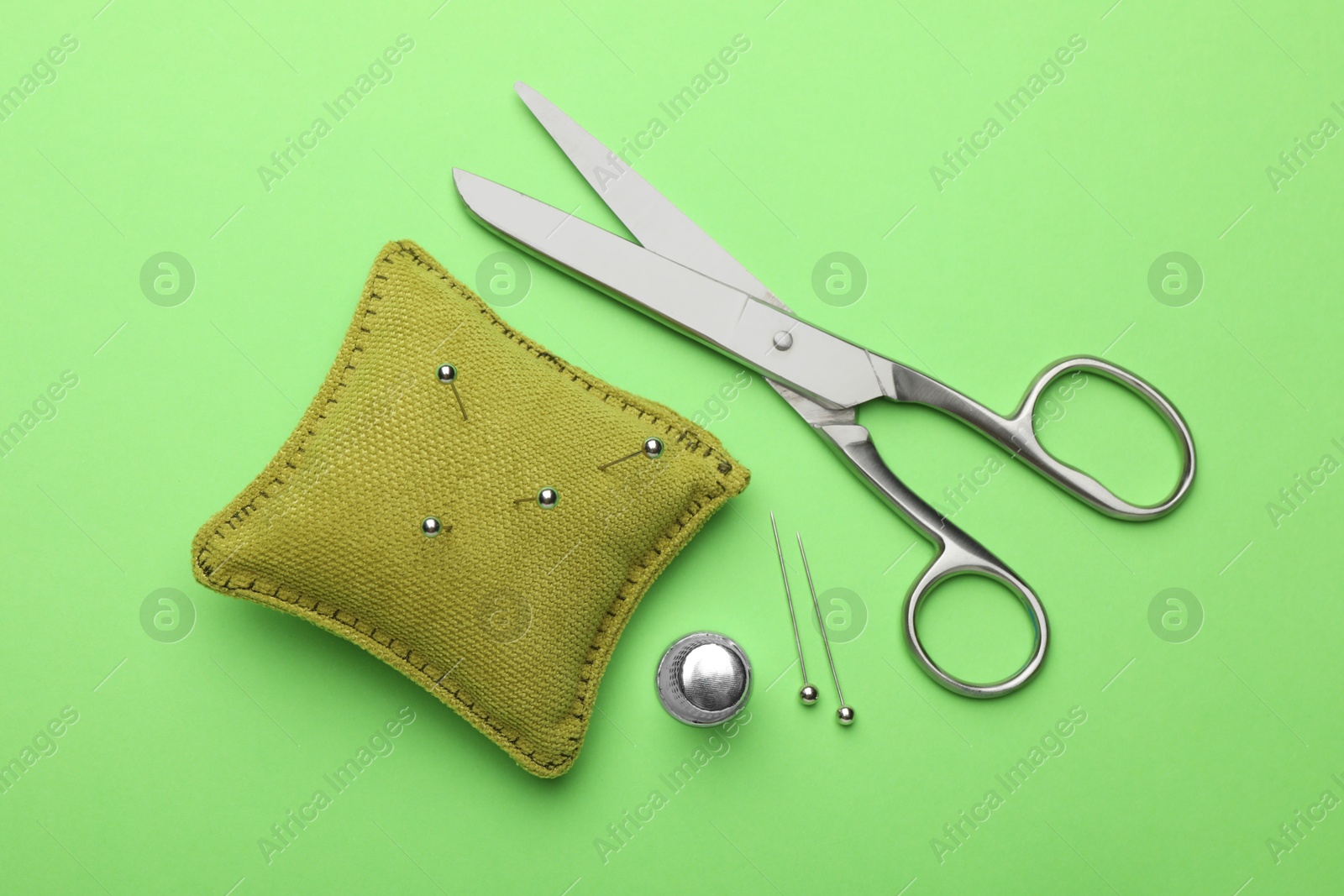 Photo of Different sewing supplies on green background, flat lay