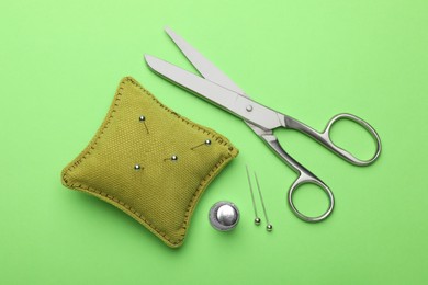 Photo of Different sewing supplies on green background, flat lay