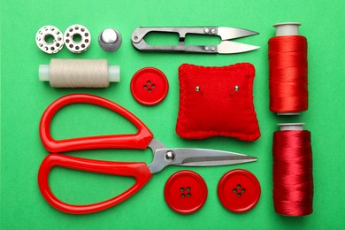 Photo of Different sewing supplies on green background, flat lay