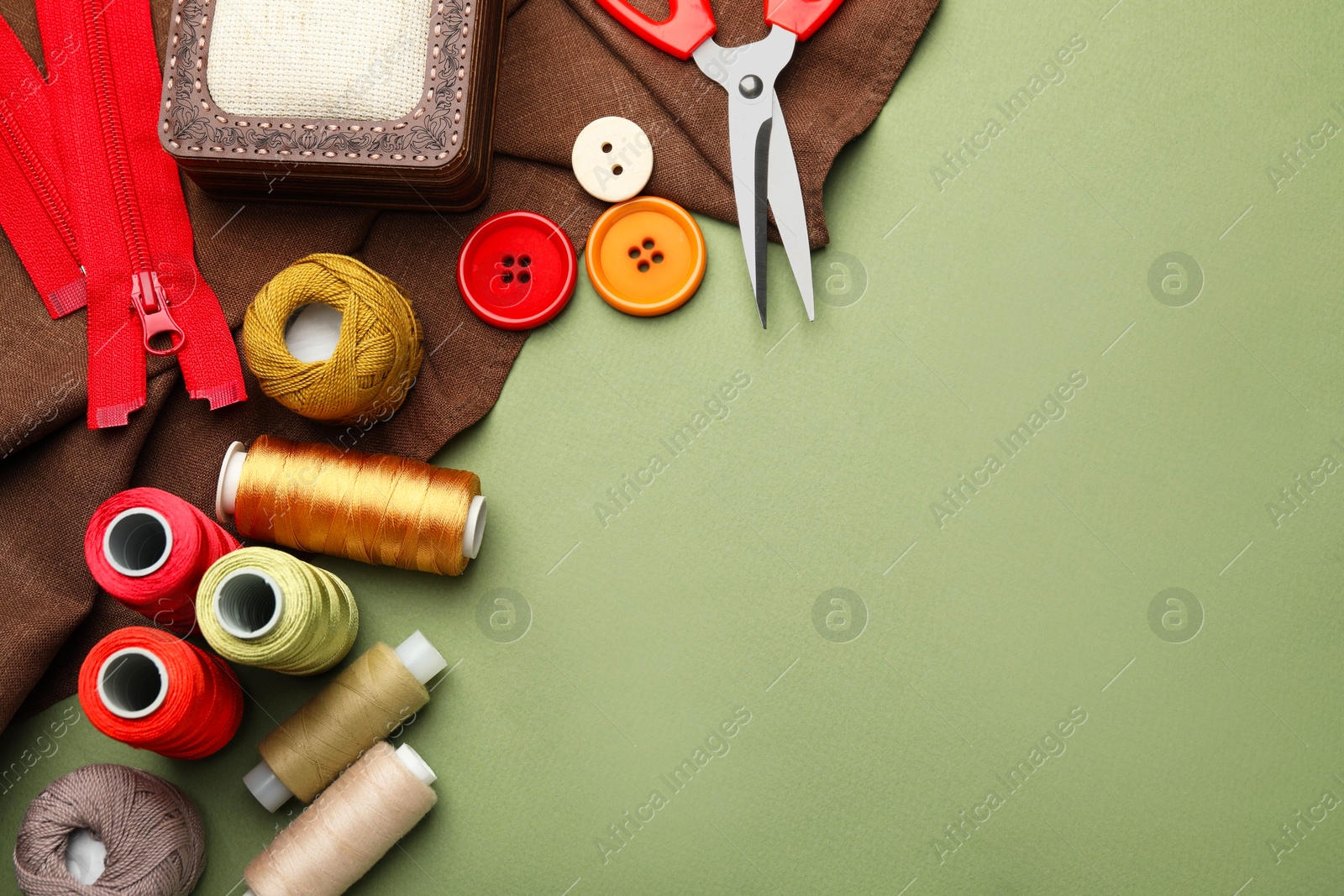 Photo of Different sewing supplies on olive background, flat lay. Space for text