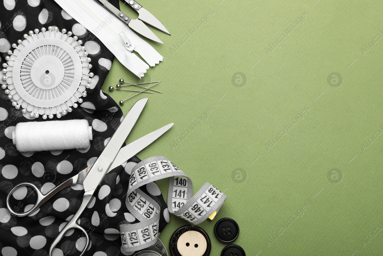 Photo of Different sewing supplies on olive background, flat lay. Space for text