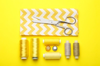 Photo of Different sewing supplies on yellow background, flat lay