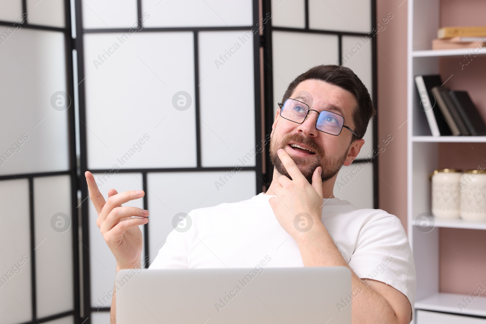 Photo of Smiling online speaker streaming webinar with laptop indoors