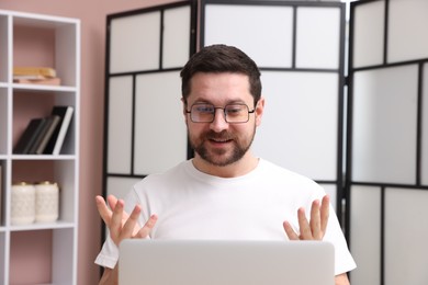 Photo of Smiling online speaker streaming webinar with laptop indoors