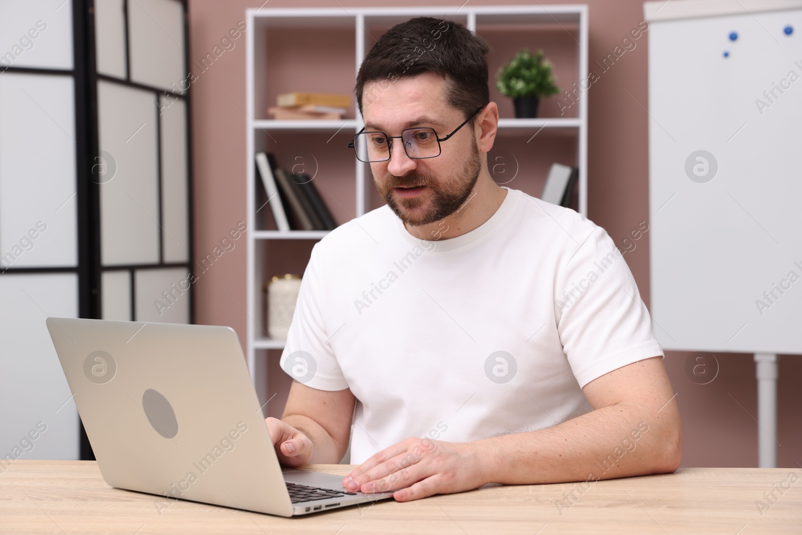 Photo of Online speaker streaming webinar with laptop at table indoors