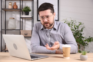 Photo of Online speaker streaming with laptop at table indoors