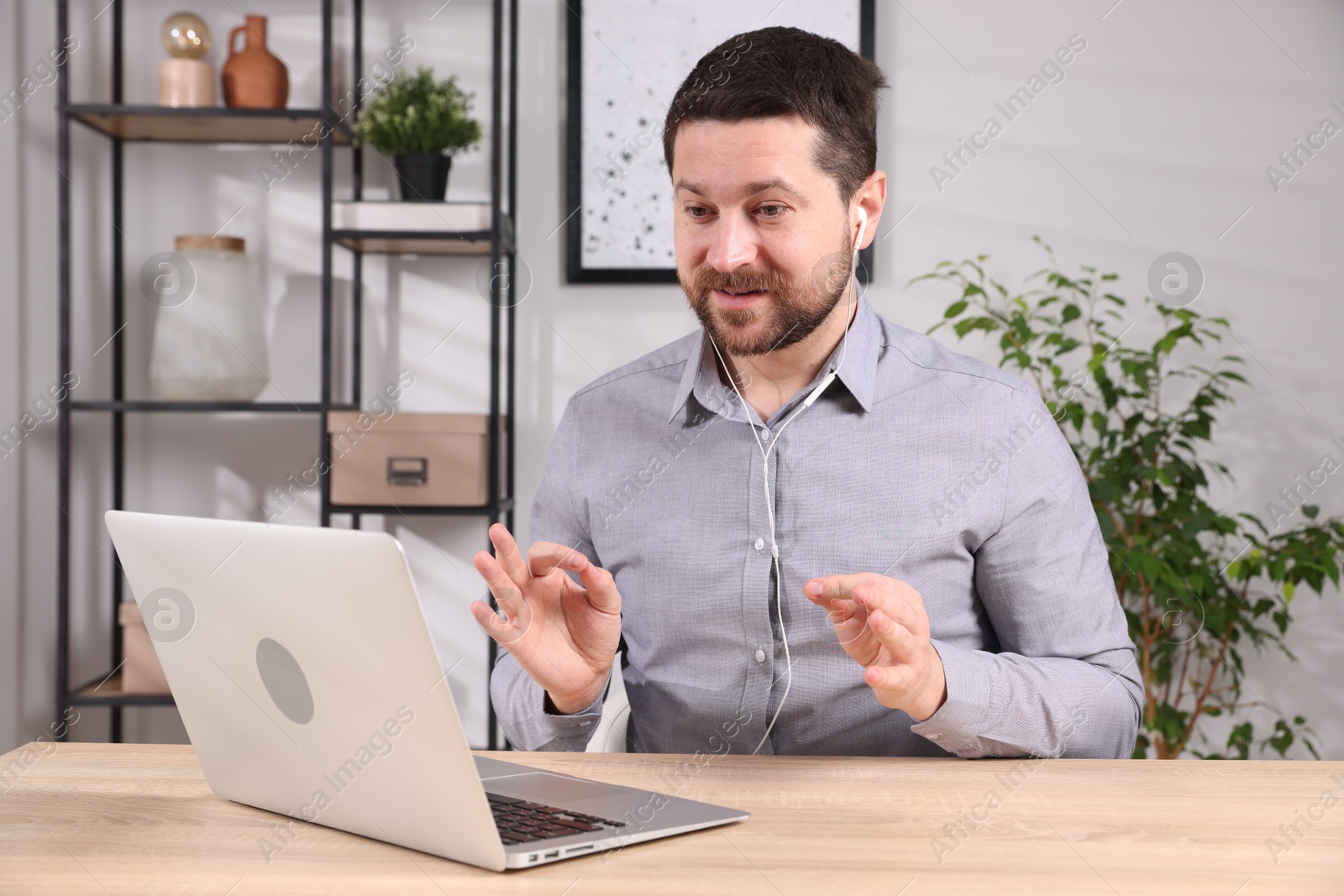 Photo of Online speaker streaming with laptop at table indoors